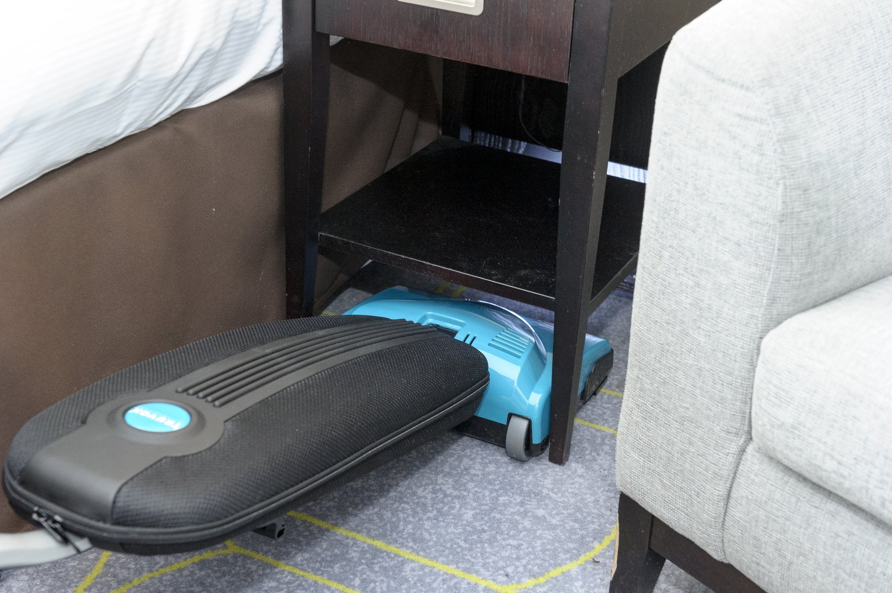 Truvox Valet Battery Upright II laid flat to reach under a bedside table in a care home bedroom